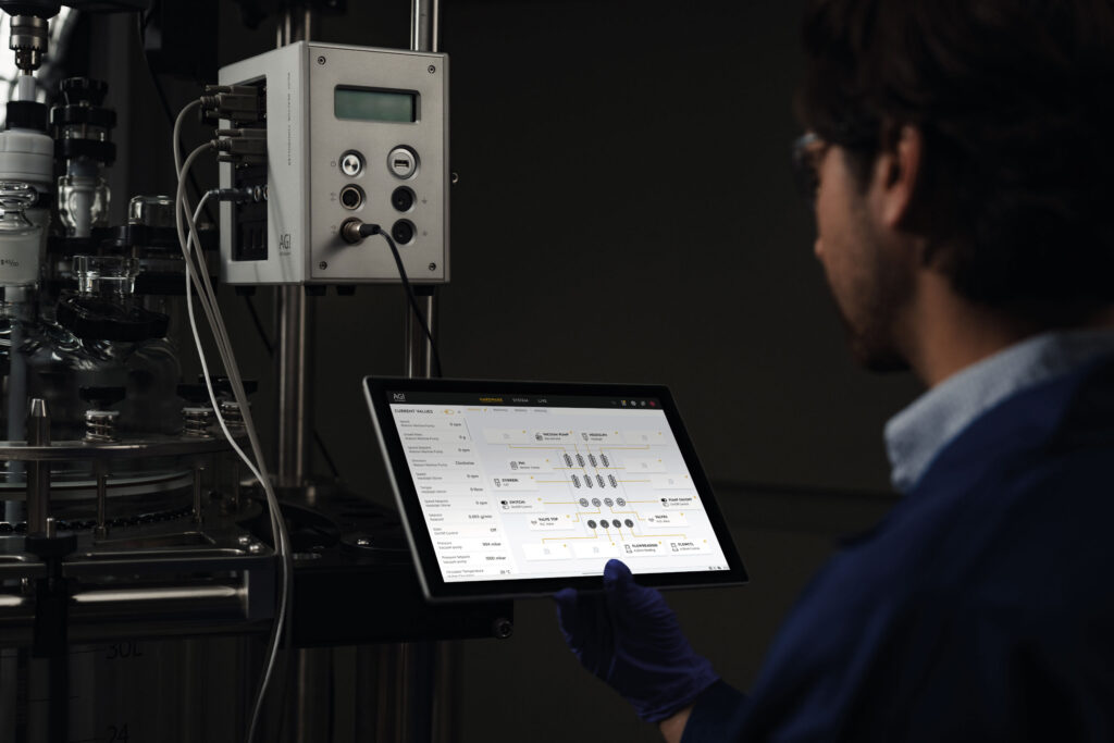 AGI Glassplant Pilot Reactor Controller chemist in lab with tablet.